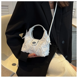 Close-up of white quilted canvas crossbody bag with silver buckle and frayed edges detail