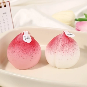 Realistic peach-shaped scented candles in pink and cream on a decorative ceramic tray