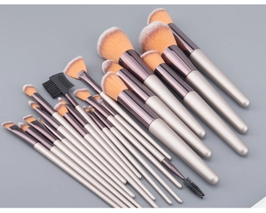 Set di 18 pennelli da trucco color champagne con setole bicolore su sfondo grigio