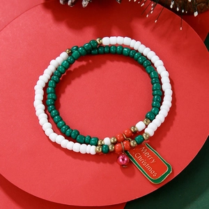 Close-up of a festive Christmas beaded bracelet with a Merry Christmas charm on red card