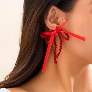 Close-up of red silk bow earrings with translucent beaded fringe on model's ear