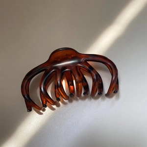 Detailed top view of leopard print hair claw with natural light and shadow on white surface