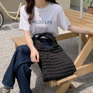 Black bubble texture fabric tote bag shown in an outdoor lifestyle setting on a model