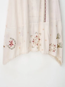 Detailed embroidery and hollow-out lace on beige linen dress for a bohemian style