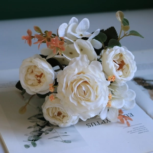 Detailed view of artificial white silk roses and hydrangeas on an open vintage book page