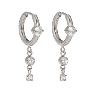 Macro detail of silver titanium earrings featuring cubic zirconia hoops and hanging tassels