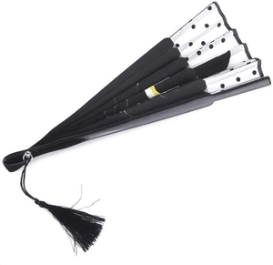 Detail of a black folding fan with white polka dots, abstract patterns, and black tassel