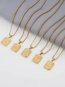 Primer plano de cinco colgantes de letras bañados en oro 18K con bordes texturizados