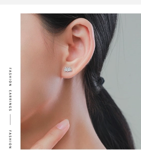 Close-up of geometric fan silver stud earrings with triple stone design worn on earlobe