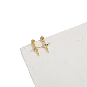 Minimalist evil eye cross earrings in gold finish with blue stones on a white block