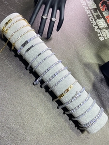 Close-up of sparkling tennis chains with white zircons on a grey velvet jewelry display stand