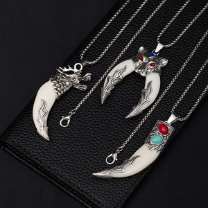 Detail of vintage wolf tooth necklaces with dragon and feline heads on leather