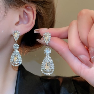 Macro detail of silver drop tassel earrings with sparkling crystals for elegant evening wear