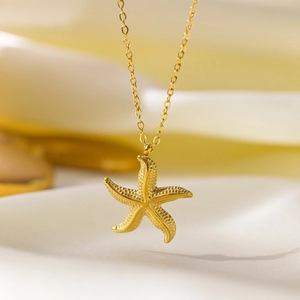 Macro shot of gold starfish pendant necklace on white silk with cross chain details