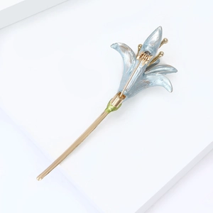 Close-up of blue enamel narcissus flower brooch with golden stem on white background