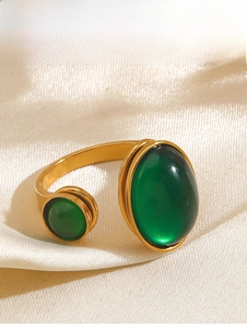 Detail of open gold ring with dual green oval stones on premium white silk fabric