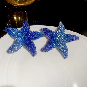 Macro shot of starfish earrings with blue gradient crystals on a white plate