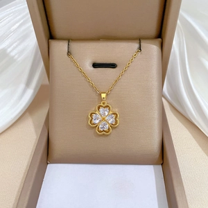 Close-up of golden four-leaf clover pendant with heart-shaped crystals in a jewelry box