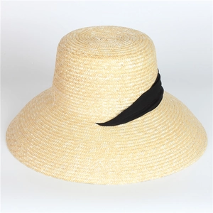 Detail of hand-woven wide brim straw hat featuring elegant black ribbon and fine texture