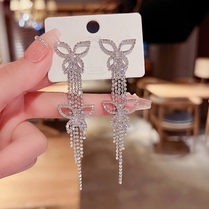 Detailed macro shot of long silver tassel earrings with crystal butterfly motifs