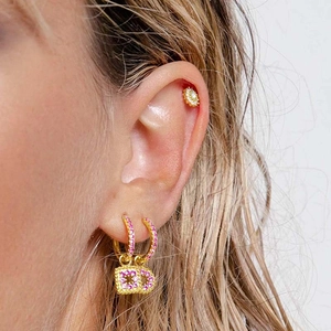Close-up of gold geometric earrings with pink pavé crystals and sparkling zircon details
