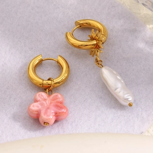 Detailed shot of asymmetric 18K gold earrings with pink flower and baroque pearl pendants