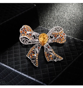 Macro detail of luxury bow brooch with orange and yellow rhinestones on black gift box