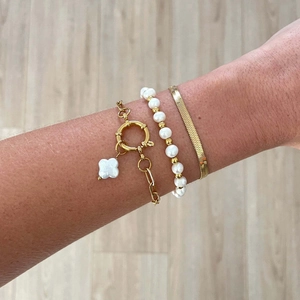 Detailed stack of gold snake chain, pearl beads, and lucky clover charm bracelet