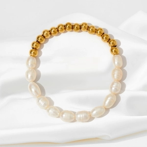 Détail du bracelet en perles baroques et perles dorées sur tissu en satin blanc élégant