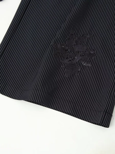 Vue détaillée du blazer noir à rayures avec broderie florale à paillettes et texture fine