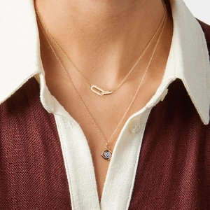Detail of layered gold necklaces with evil eye pendant and diamond rectangle links on model