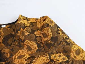 Macro-opname van de gouden jacquardstof en het maatlabel S op een elegante jurk met V-hals