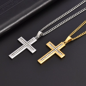 Dettaglio delle collane con croce in oro e argento con cristalli su sfondo nero