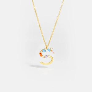 Macro shot of gold S-letter pendant with colorful gemstones and white diamonds necklace