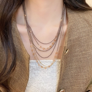 Close-up of layered bronze necklaces with amber crystal beads on elegant model