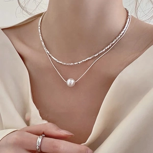 Vue détaillée du collier double argenté avec pendentif perle sur le cou du mannequin