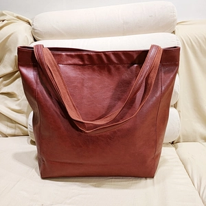 Détail macro du sac cabas en cuir souple marron avec ses bandoulières en tissu