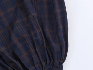Detail of dark blue and coffee plaid woven fabric with elastic hem and twill texture