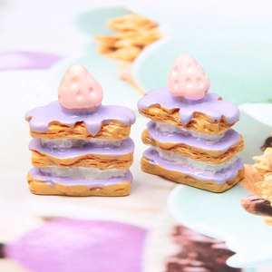 Macro shot of miniature strawberry Napoleon cake resin models with purple cream detail