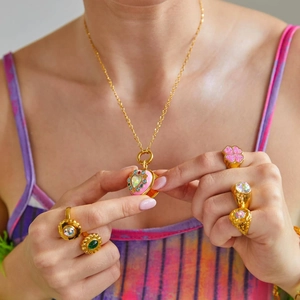 Close-up of gold heart locket necklace with pink enamel and colorful rhinestones