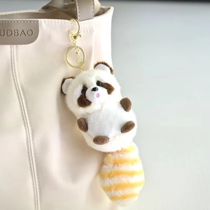 Schattige pluizige wasbeer pluche sleutelhanger met gestreepte staart aan een tas