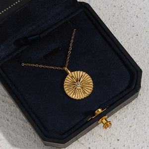 Golden sunburst round pendant necklace with clear gem in a blue velvet gift box