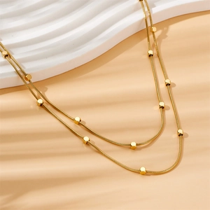 Golden double layered snake chain necklace with square beads in warm lighting