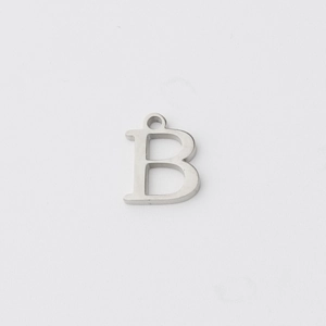Detailed macro view of silver polished stainless steel letter B pendant with ring