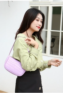 Close-up of purple faux crocodile pattern texture and golden hardware on hobo bag