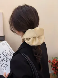 Close-up of cream jacquard satin scrunchie with floral embroidery in a ponytail