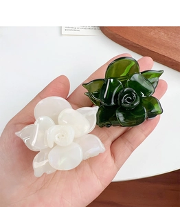 Detailed view of white and dark green acetate rose hair claws with glossy finish