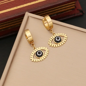 Golden eye-shaped hoop earrings with black and white enamel in a beige jewelry gift box
