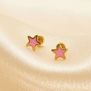 Detailed close-up of gold star earrings with pink enamel inlay on satin background