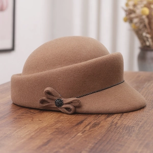 Close-up of wool felt equestrian hat with a bow detail and bead chain on wood surface